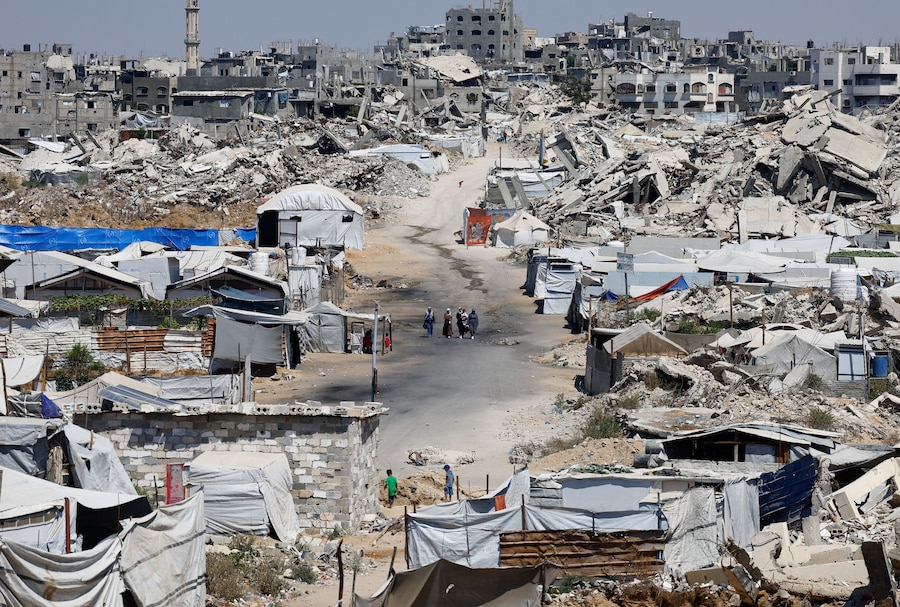 Alcune persone camminano in un luogo distrutto durante l’offensiva israeliana, a Beit Lahiya, nella parte settentrionale della Striscia di Gaza. (REUTERS/Mahmoud Issa)