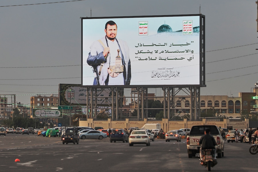 Alcuni veicoli transitano nei pressi di un cartellone pubblicitario che raffigura il leader houthi Abdul Malik al-Houthi con un messaggio in arabo che recita: “L’inazione e la resa non offrono alcuna protezione alla nazione”, a Sana’a, nello Yemen, martedì 18 agosto 2026. (AP/Osamah Abdulrahman/Associated Press/ LaPresse/APN)