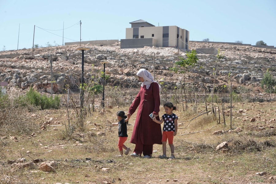 Roqayya, moglie di Loui Ridi, proprietario immobiliare palestinese-americano residente in Ohio, cammina con le loro figlie, Kinda, 2 anni, a sinistra, e Hoor, 4 anni, davanti alla loro casa, assediata da oltre una settimana dai coloni israeliani, nel villaggio di Qusra, in Cisgiordania occupata, a sud di Nablus. (AP/Majdi Mohammed/Associated Press/ LaPresse/APN)