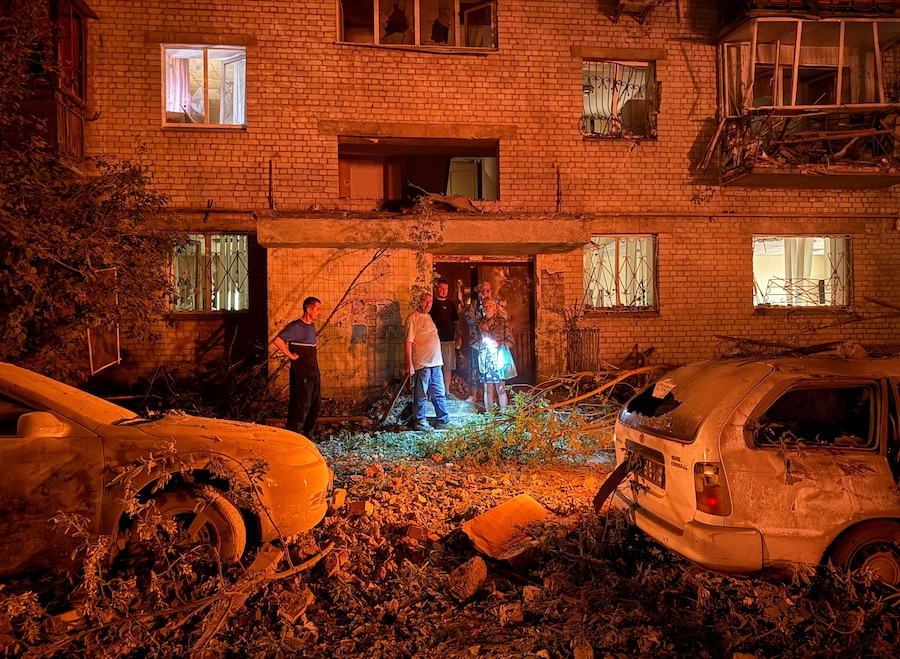 Alcuni residenti si trovano sul luogo di un condominio colpito da un missile russo, nel contesto dell'attacco della Russia all'Ucraina, a Kiev. (REUTERS)