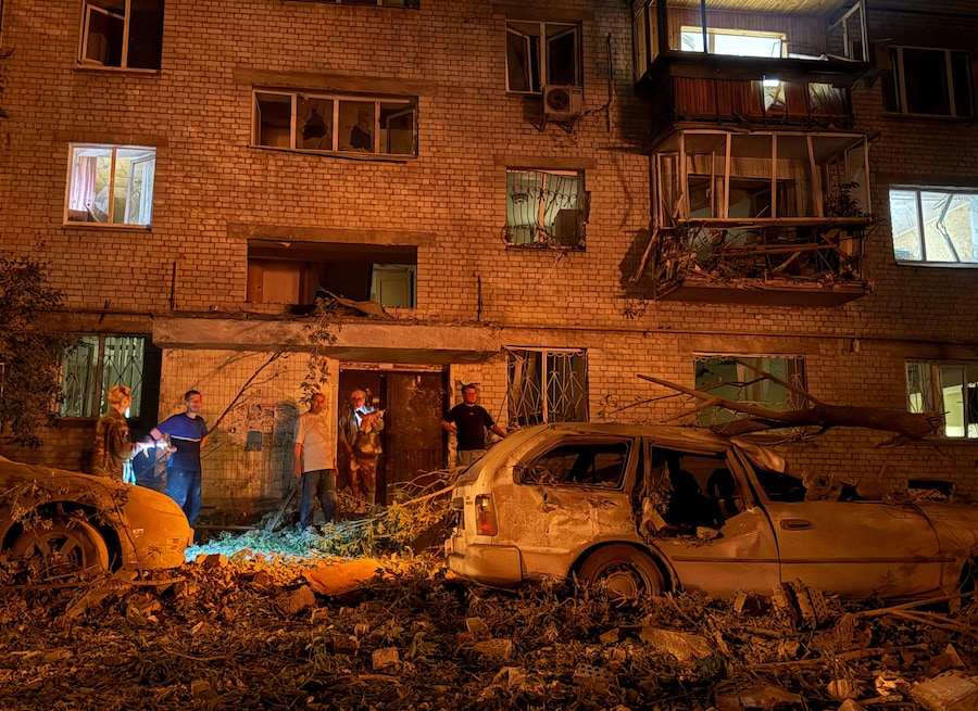 Alcuni residenti si trovano sul luogo di un condominio colpito da un missile russo, nel corso dell’attacco della Russia all’Ucraina, a Kiev, Ucraina. (REUTERS)