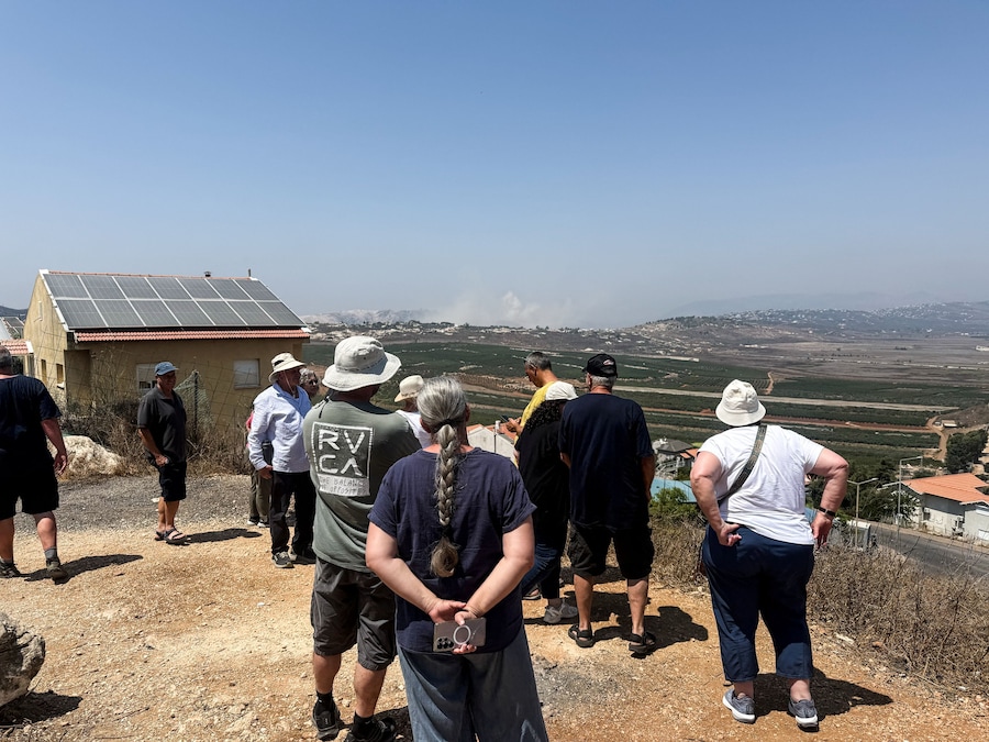 Da un belvedere al confine tra Israele e Libano, alcune persone osservano il fumo che si alza in Libano in seguito a un'esplosione avvenuta sul versante libanese (REUTERS)