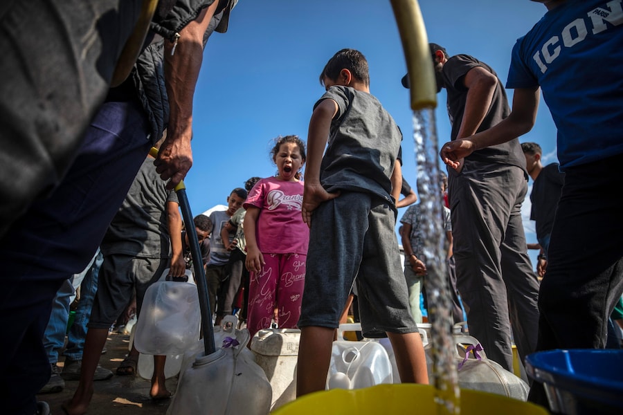 I palestinesi sfollati fanno la fila per ritirare l’acqua potabile in un campo profughi nel centro di Gaza City (EPA)