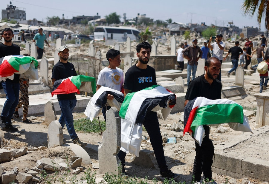 I palestinesi trasportano i resti dei corpi mentre partecipano al funerale di 50 persone appartenenti a tre famiglie, uccise durante la guerra e i cui corpi sono stati recuperati di recente dalle macerie, nella città di Gaza (REUTERS)