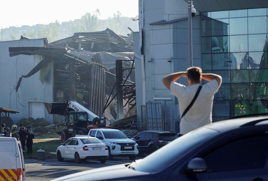 Un residente osserva i soccorritori all’opera sul luogo di un centro commerciale distrutto dall’attacco con droni russi nella città di Kryvyi Rih, nella regione di Dnipropetrovsk, Ucraina (REUTERS)