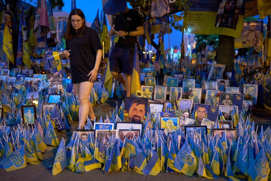 Nel centro di Kiev, la gente cammina accanto a bandiere ucraine e fotografie esposte in memoria dei civili e dei soldati uccisi durante la guerra con la Russia (APN)