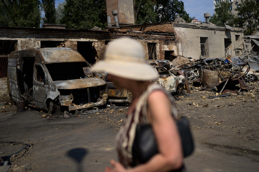 Un residente del posto passa accanto a veicoli distrutti e detriti sparsi il giorno dopo un attacco con missili e droni russi a Kiev (APN)