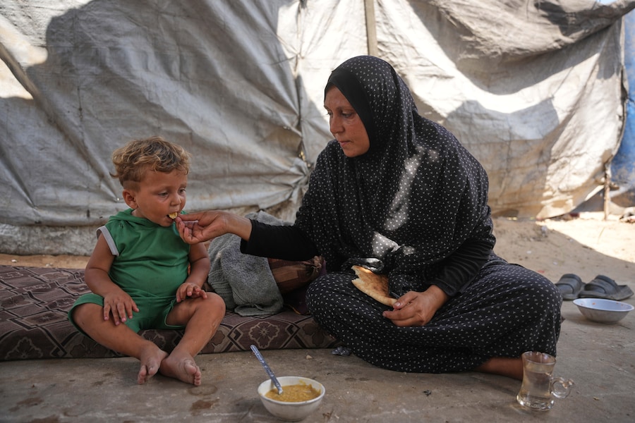 Una donna palestinese dà da mangiare a un bambino a Deir al-Balah, nella Striscia di Gaza centrale (APN)