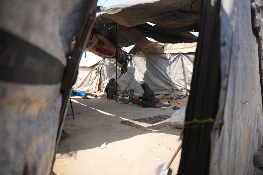 Una donna palestinese dà da mangiare a un bambino un pasto preparato con materiali combustibili raccolti da una discarica, a causa della carenza di gas da cucina, in una tenda a Deir al-Balah, nella Striscia di Gaza centrale (APN)