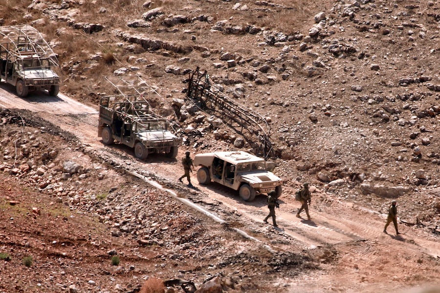 Soldati israeliani e veicoli blindati operano nella zona di Wadi al-Slouki, vista dal villaggio di Chaqra, nel Libano meridionale (EPA)