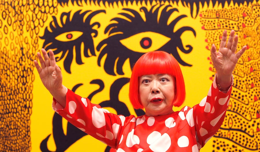 L'artista giapponese Yayoi Kusama posa per i fotografi davanti al suo dipinto "L'amore arriva sulla Terra portando con sé una storia del cosmo" alla Tate Modern di Londra, il 7 febbraio 2012. (AP Photo/Kirsty Wigglesworth, Archivio/Associated Press / LaPresse/APN)