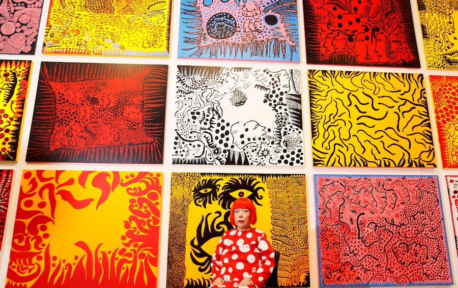 L'artista giapponese Yayoi Kusama posa per i fotografi davanti al suo dipinto “Love Arrives at the Earth Carrying with it a Tale of the Cosmos” (in basso al centro) e ad altri dipinti alla Tate Modern di Londra, martedì 7 febbraio 2012. (AP Photo/Kirsty Wigglesworth, Archivio/Associated Press / LaPresse/APN)