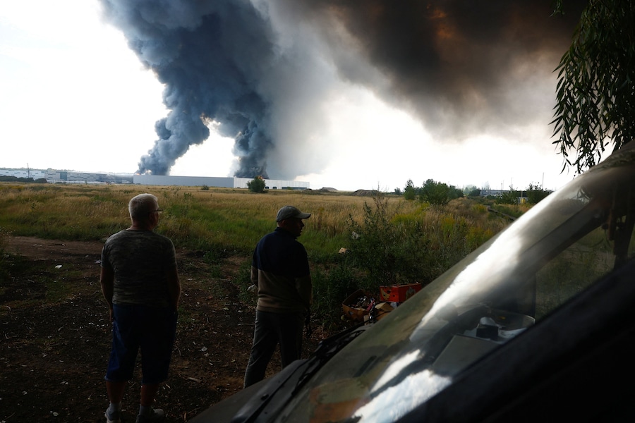 La gente osserva da vicino il fumo che si alza sopra un magazzino, colpito da un attacco con droni russi nel contesto dell'offensiva russa contro l'Ucraina, nella regione di Kiev. (REUTERS/Valentyn Ogirenko)