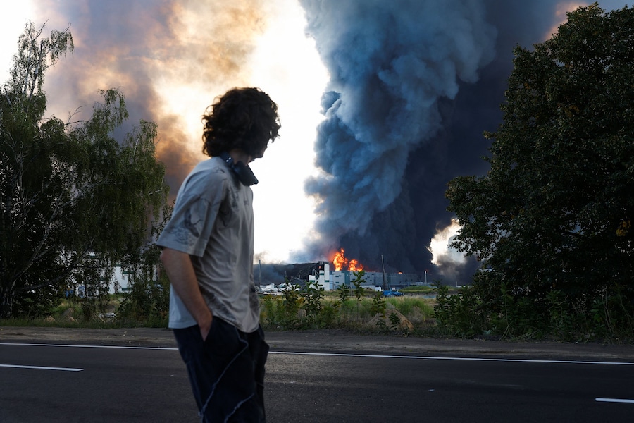 Un uomo osserva il fumo che si alza sopra un magazzino, colpito da un attacco con droni russi, nella regione di Kiev. (REUTERS/Valentyn Ogirenko)