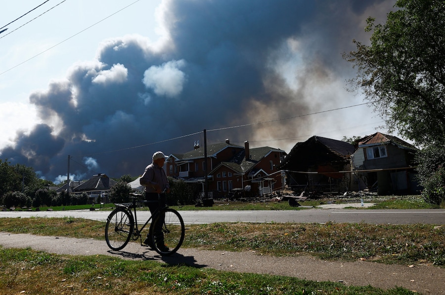 Un abitante in sella alla sua bicicletta cammina nei pressi di alcune abitazioni danneggiate durante un attacco con droni russi, nella regione di Kiev. (REUTERS/Valentyn Ogirenko)