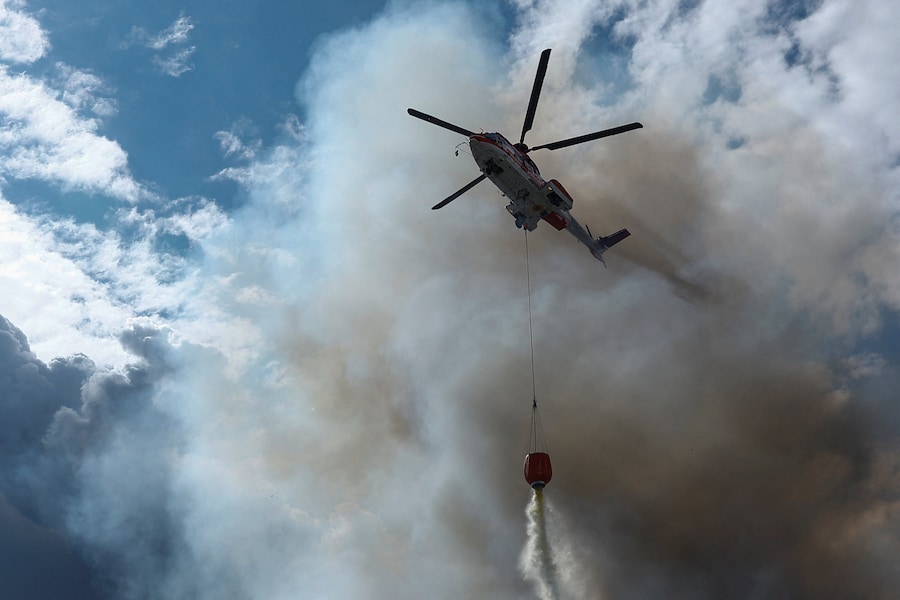 Un elicottero antincendio scarica acqua su un magazzino colpito da un attacco con droni russi, nella regione di Kiev. (REUTERS/Valentyn Ogirenko)