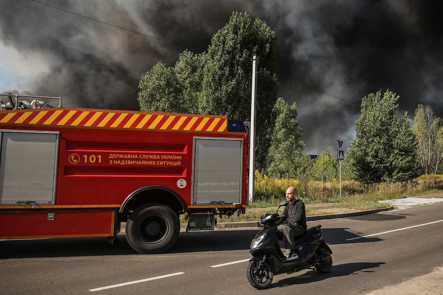 Un uomo in scooter passa davanti al luogo colpito da un drone russo mentre si alza il fumo, nella regione di Kiev, Ucraina, il 29 agosto 2026. (REUTERS/Alina Smutko)