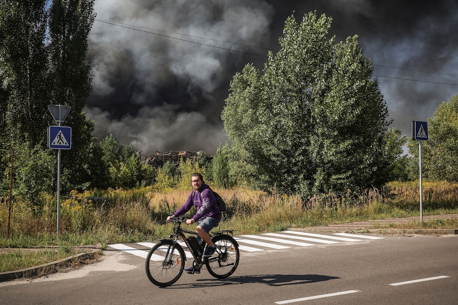 Un uomo in bicicletta passa davanti al luogo colpito da un attacco con droni russi mentre sale il fumo, nella regione di Kiev, Ucraina, il 29 agosto 2026. (REUTERS/Alina Smutko)