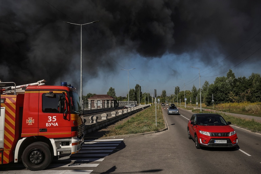 Le auto passano accanto ai vigili del fuoco, impegnati sul luogo di un attacco sferrato da un drone russo mentre il fumo si alza, nella regione di Kiev, Ucraina, il 29 agosto 2026. (REUTERS/Alina Smutko)