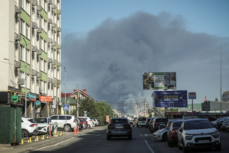 Un’auto attraversa una zona residenziale mentre sullo sfondo si alza il fumo in seguito a un attacco con droni russi, nella regione di Kiev, Ucraina, il 29 agosto 2026. (REUTERS/Alina Smutko)