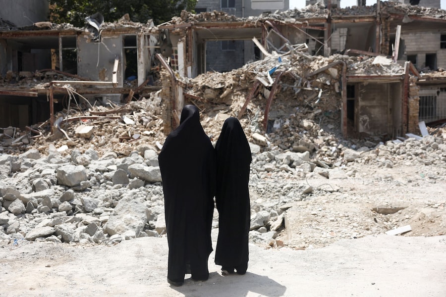 Alcune donne iraniane osservano un edificio danneggiato durante un attacco statunitense e israeliano avvenuto a Teheran, in Iran. (Majid Asgaripour/WANA (West Asia News Agency) via REUTERS)
