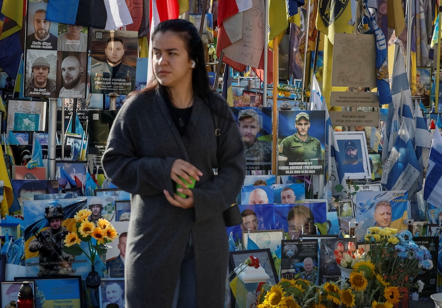 Una donna visita un memoriale improvvisato dedicato ai difensori ucraini caduti in Piazza dell'Indipendenza, mentre il Paese celebra la Giornata della Memoria dei Difensori, nel contesto dell'attacco russo all'Ucraina, a Kiev. (REUTERS/Gleb Garanich)