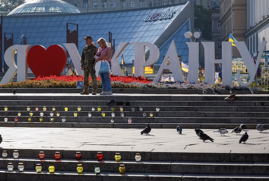 La gente osserva un minuto di silenzio davanti a un memoriale improvvisato dedicato ai difensori ucraini caduti in Piazza dell’Indipendenza, mentre il Paese celebra la Giornata della Memoria dei Difensori, sullo sfondo dell’attacco russo all’Ucraina, a Kiev. (REUTERS/Gleb Garanich)