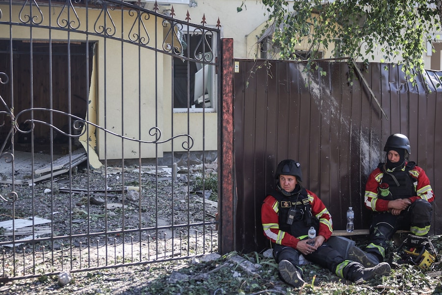 I soccorritori, durante una pausa, osservano nei pressi di una casa danneggiata sul luogo di un attacco sferrato da un drone russo, contro l'Ucraina, nel villaggio di Myla, nella regione di Kiev. (REUTERS/Alina Smutko)