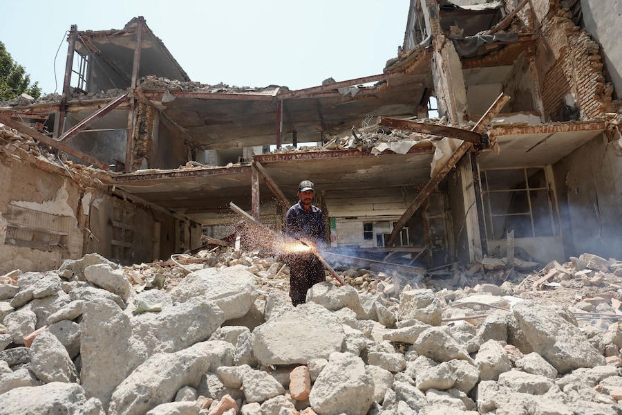 Un uomo lavora nei pressi di un edificio danneggiato durante un attacco statunitense e israeliano, a Teheran. (Majid Asgaripour/WANA (West Asia News Agency) via REUTERS)
