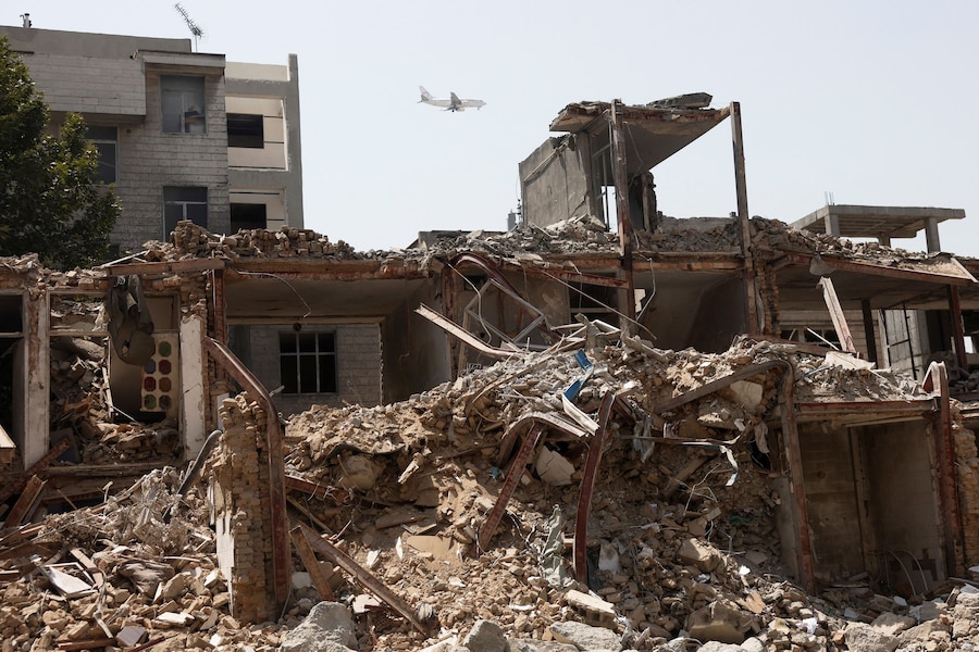 Un aereo sorvola un edificio danneggiato durante un attacco statunitense e israeliano, a Teheran. (Majid Asgaripour/WANA (West Asia News Agency) via REUTERS)