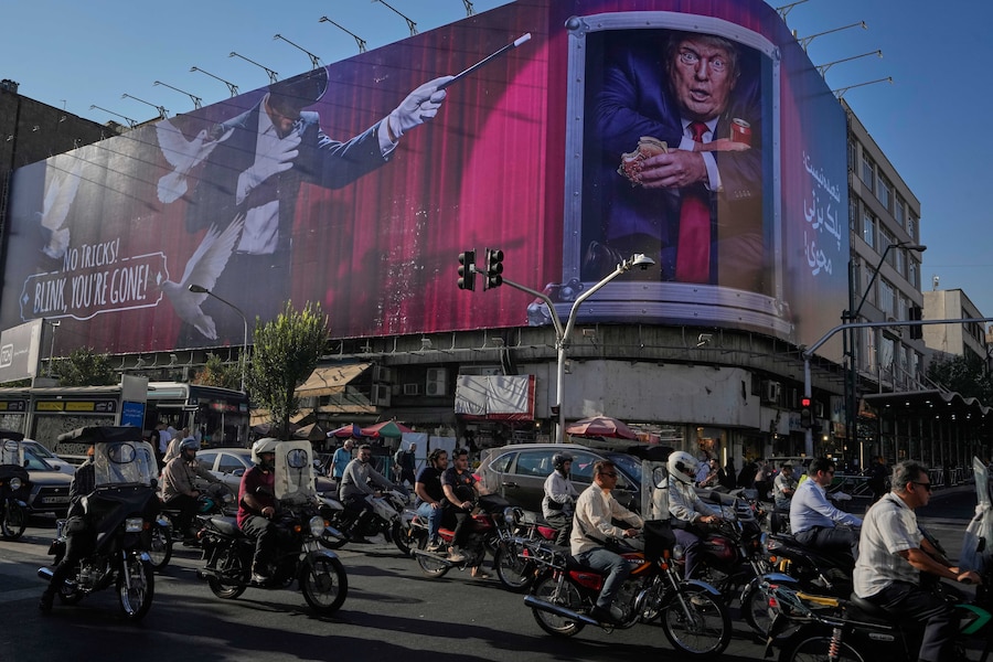Nel centro di Teheran, in Iran, alcuni motociclisti passano davanti a un cartellone pubblicitario che raffigura il presidente degli Stati Uniti Donald Trump all’interno di un container adibito a servizio di catering. (Foto AP/Vahid Salemi/APN)