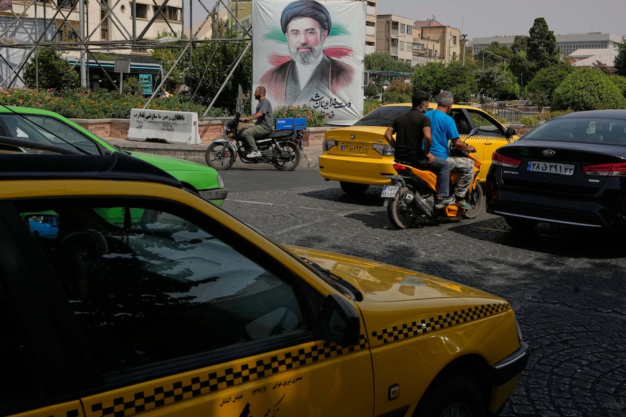Nel centro di Teheran, in Iran, alcuni veicoli passano davanti a uno striscione che raffigura il ritratto della Guida Suprema iraniana, l'ayatollah Mojtaba Khamenei. (APN)