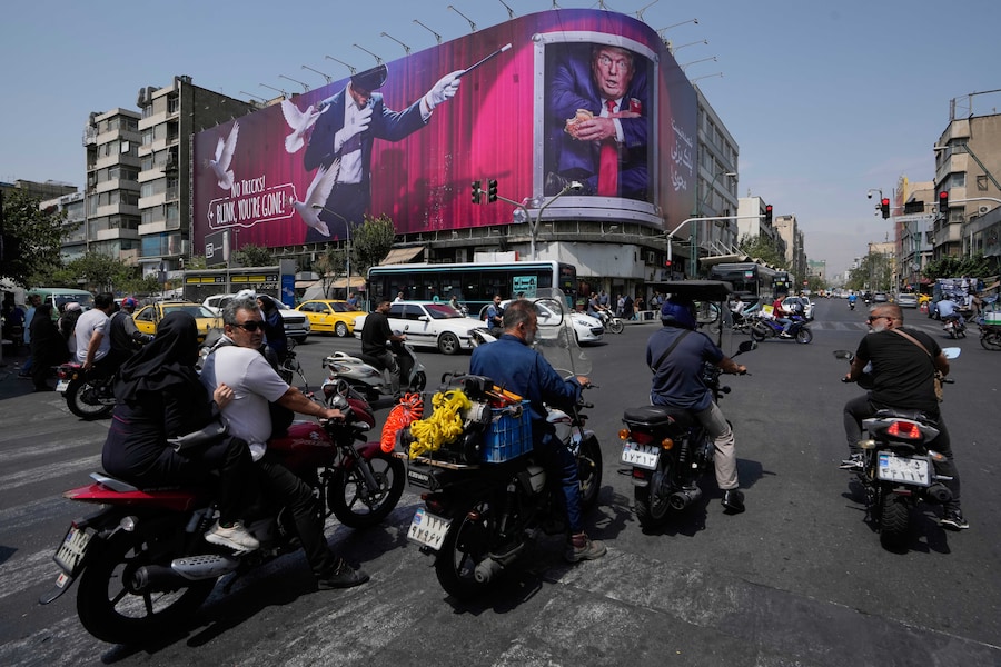 Nel centro di Teheran, in Iran, alcuni veicoli passano davanti a un cartellone pubblicitario che raffigura il presidente degli Stati Uniti Donald Trump all’interno di un container per il catering, affiancato da un mago, con la scritta “Niente trucchi! Se sbatti le palpebre, sei sparito” (APN)