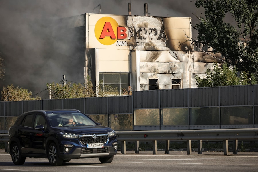 Un'auto passa accanto a un magazzino colpito da un attacco con droni russi, con l'insegna "Avrora Multimarket" fusa, nel contesto dell'attacco della Russia all'Ucraina, nella regione di Kiev. (REUTERS)