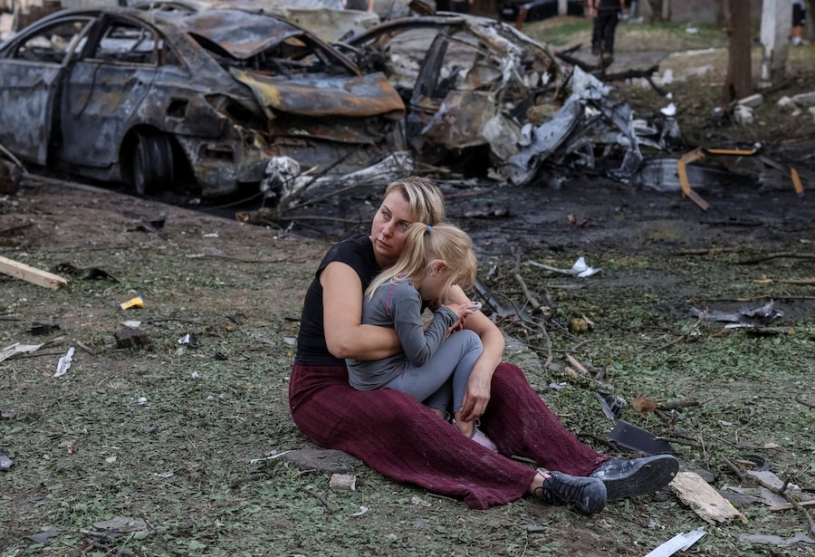 Nataliia, una residente, e sua figlia Elia, di 6 anni, sono sedute davanti a un condominio danneggiato da un attacco missilistico russo, nel contesto dell'offensiva russa contro l'Ucraina, nella città di Borispil, in Ucraina. (REUTERS)
