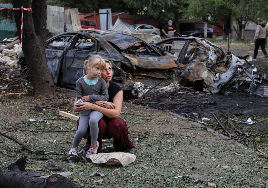 Nataliia, una residente, e sua figlia Elia, di 6 anni, sono sedute sul luogo di un condominio danneggiato da un attacco missilistico russo, nel contesto dell'offensiva russa contro l'Ucraina, nella città di Borispil. (REUTERS)