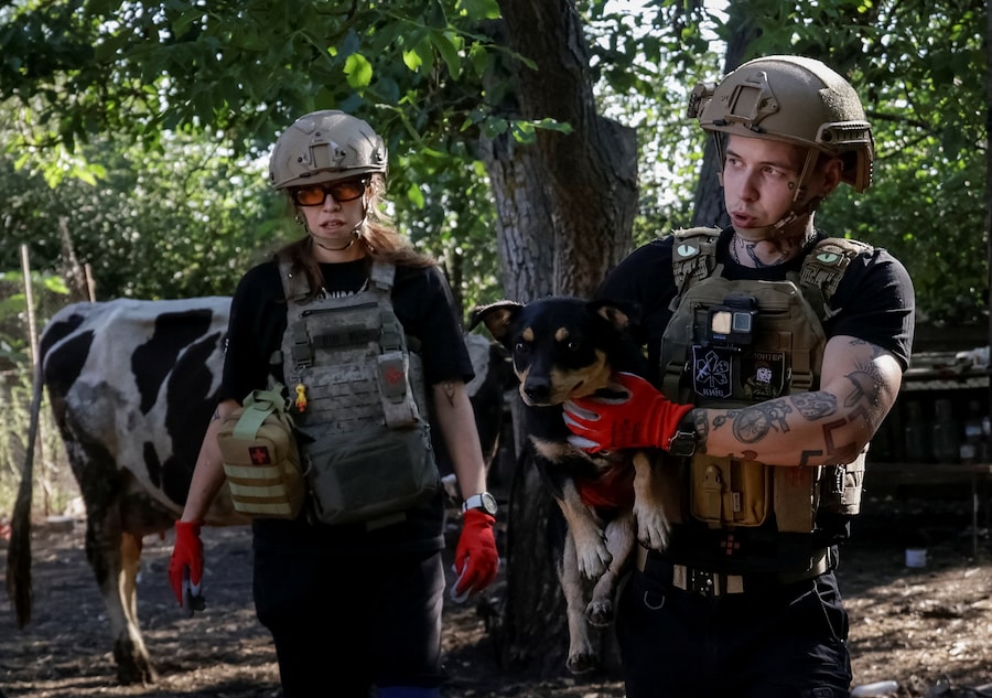 Un volontario dell’organizzazione ucraina per il salvataggio degli animali UAnimals trasporta un cane mentre aiuta Anatolii Zubko, 53 anni, a evacuare dal suo villaggio natale di Hroza, nella regione di Kharkiv, Ucraina (REUTERS)