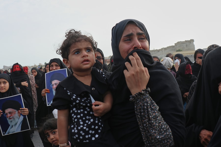 Una donna con un bambino in braccio piange durante un funerale di massa in memoria delle vittime di un attacco in cui, secondo i media iraniani e un’organizzazione per i diritti umani, un missile statunitense ha colpito un’abitazione in cui si stava celebrando un matrimonio a Kuhestak, nel sud dell’Iran. (APN)