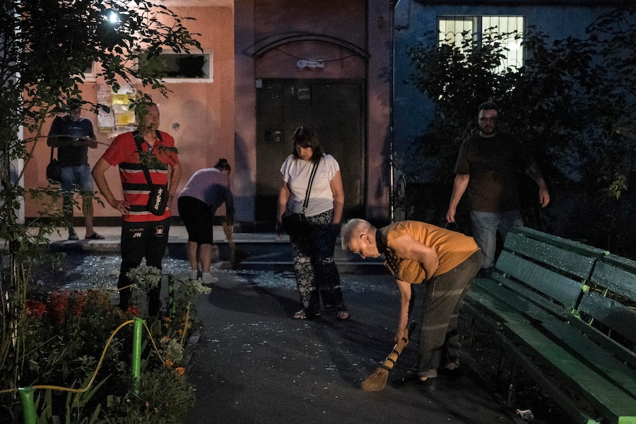Alcuni residenti ripuliscono le macerie sul luogo di un attacco sferrato da un drone russo contro un edificio residenziale di nove piani a Kiev. (EPA)