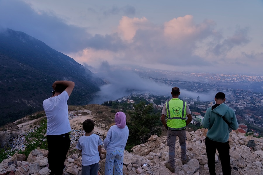 La gente osserva il fumo che si alza provocato da un attacco aereo israeliano che ha colpito un'abitazione nel villaggio di Araba Salim, nel sud del Libano (APN)