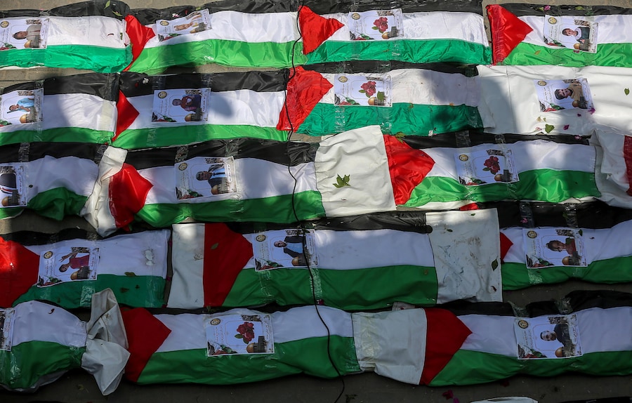 I corpi coperti di 100 palestinesi, tra cui decine di bambini, sono disposti in fila durante un funerale di massa nel quartiere di Al-Zaytun (Zeitoun) della città di Gaza, nella Striscia di Gaza (EPA)