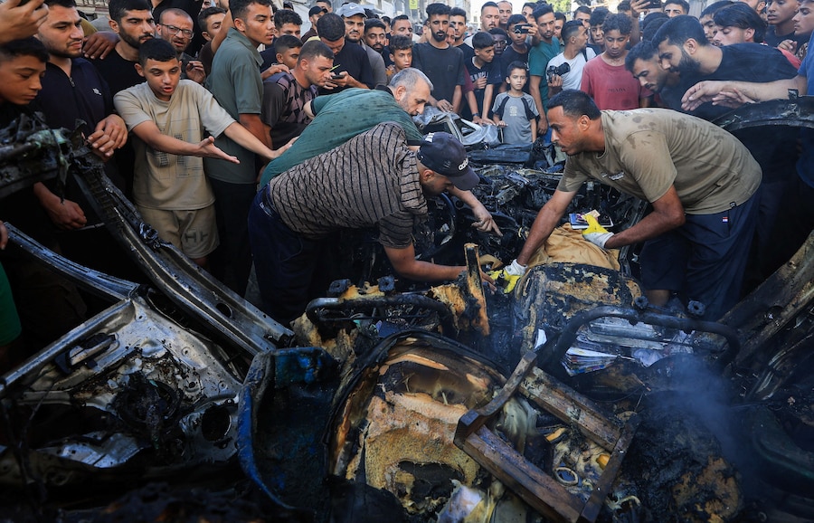 I palestinesi ispezionano il luogo in cui un veicolo è stato colpito da un attacco aereo israeliano, nella città di Gaza (REUTERS)