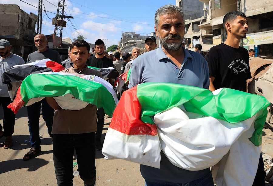 I partecipanti al funerale trasportano le salme avvolte nelle bandiere palestinesi, nel giorno del funerale collettivo dei membri delle famiglie Irahem, Malaka, Qanbour, Balawi e Dahdouh, uccisi in un attacco israeliano nel 2023 e i cui resti sono stati recuperati dalle macerie, secondo la Protezione Civile di Gaza, nella città di Gaza (REUTERS)