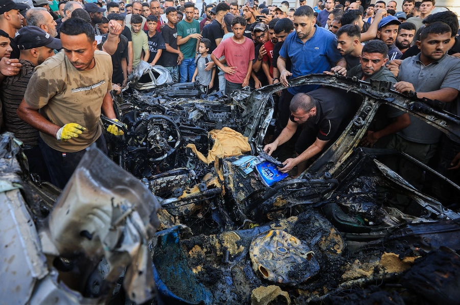 I palestinesi ispezionano il luogo in cui un veicolo è stato colpito da un attacco aereo israeliano, nella città di Gaza (REUTERS)
