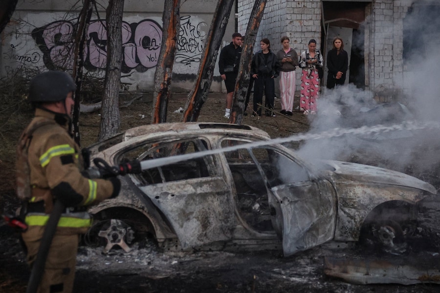 Alcuni residenti si trovano sul luogo di un attacco sferrato da missili e droni russi mentre un vigile del fuoco è al lavoro, nel contesto dell’offensiva russa contro l’Ucraina, a Kiev. (REUTERS)