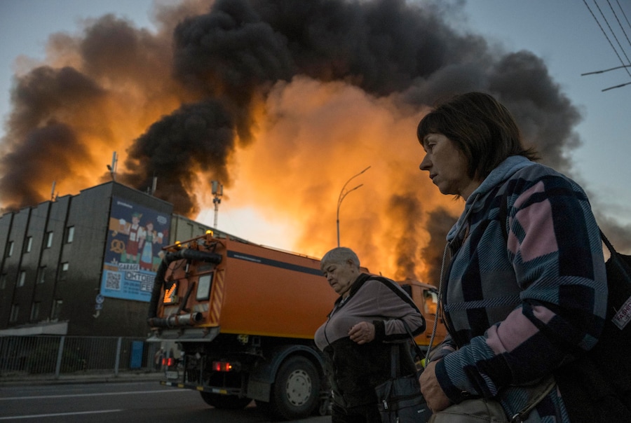 Alcune persone passano davanti al luogo colpito da un attacco russo a Kiev. (EPA)