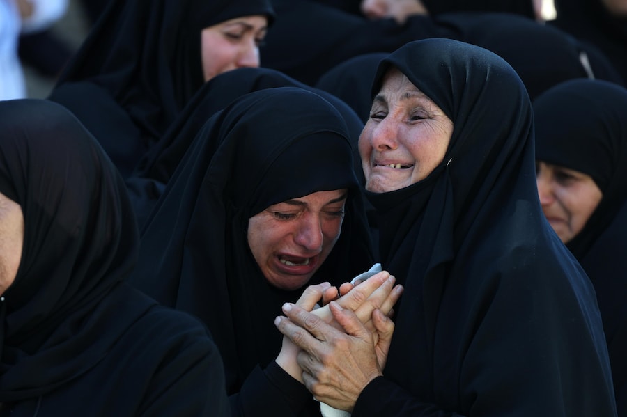 I partecipanti al funerale piangono durante il corteo funebre in memoria delle vittime di un attacco aereo israeliano nel villaggio di Kfar Rumman, nel Libano meridionale (EPA)