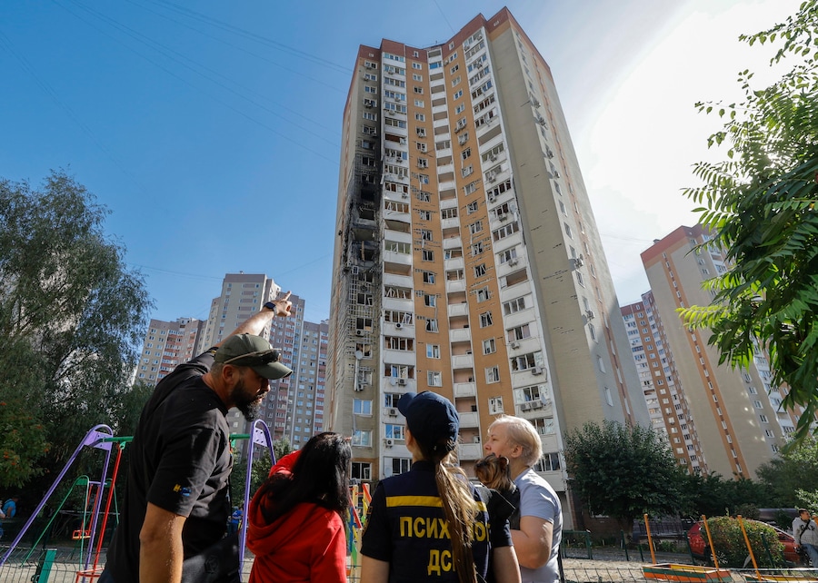 La gente sul luogo di un attacco russo contro un edificio residenziale a molti piani a Kiev (EPA)