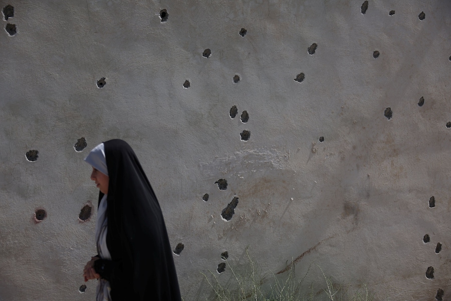 Una donna passa accanto ai segni lasciati dalle schegge sul muro di un'abitazione dopo un attacco avvenuto il 28 febbraio, a Lamerd, in Iran, il 12 settembre 2026. Majid Asgaripour/WANA (West Asia News Agency) via REUTERS (via REUTERS)