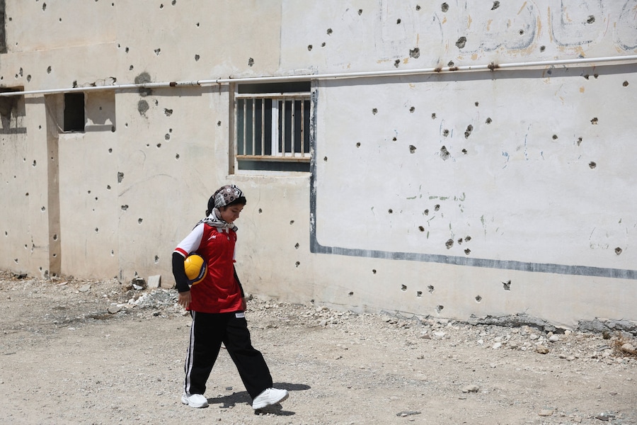 Anita Ghasemi, una ragazza iraniana ferita durante un attacco al palazzetto dello sport di Lamerd il 28 febbraio, cammina davanti a un muro segnato dai fori delle schegge, a Lamerd, in Iran, il 12 settembre 2026. Majid Asgaripour/WANA (West Asia News Agency) via REUTERS (via REUTERS)